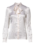 Une blouse blanche en satin dolce & gabbana avec col ascot, manches longues et un noeud délicat au col