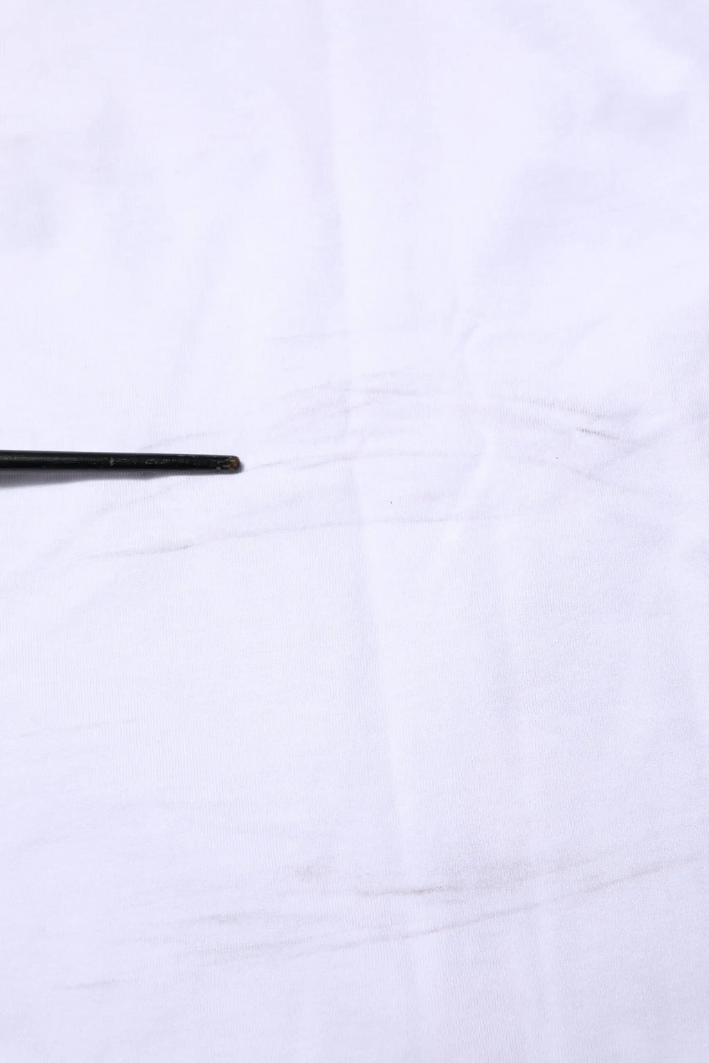 Chopsticks noirs avec surface légèrement texturée à côté d’un t-shirt dolce & gabbana camouflage blanc en coton pour homme