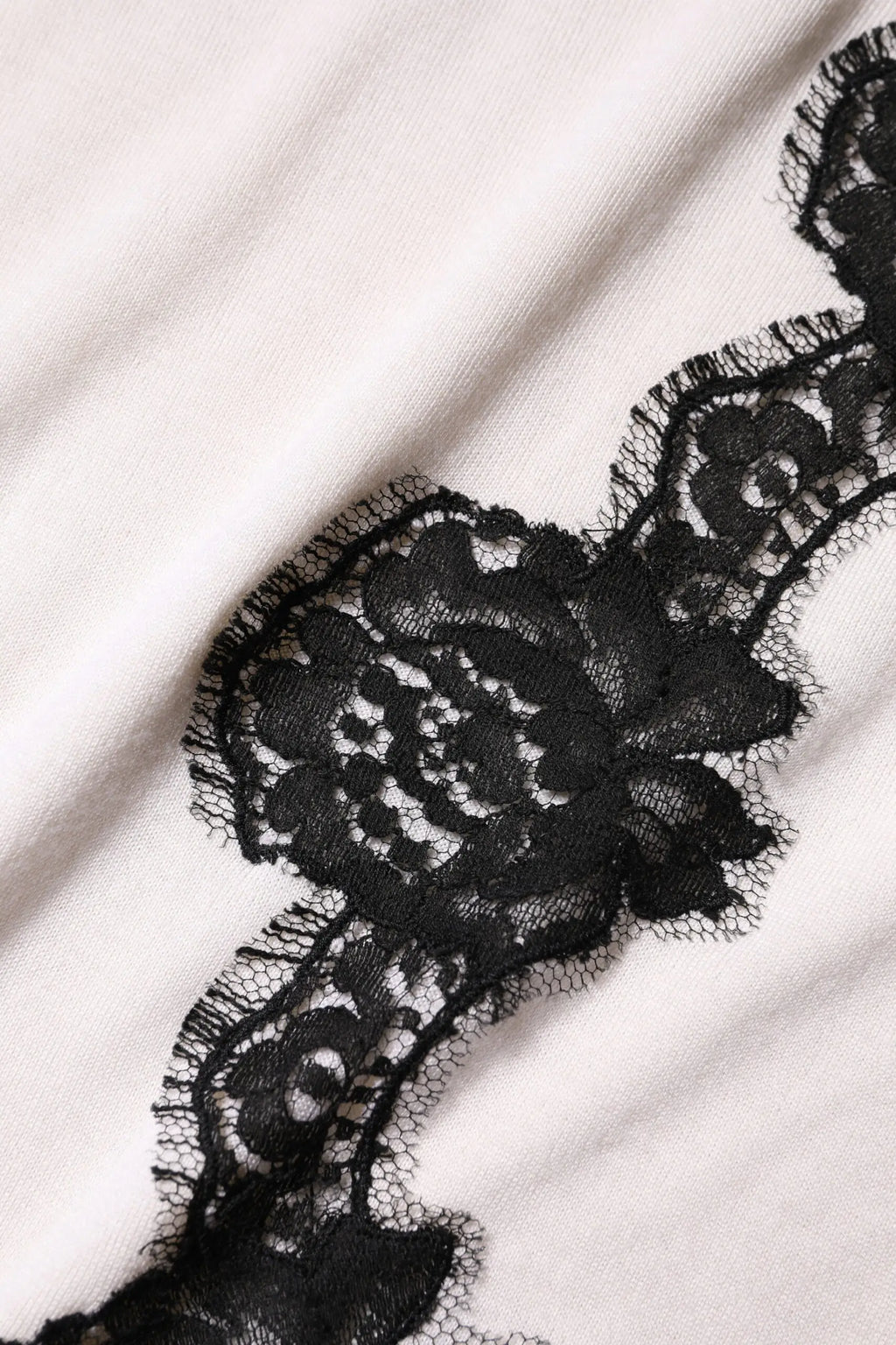 Black floral lace trim on the edge of a white cashmere dolce & gabbana tank top