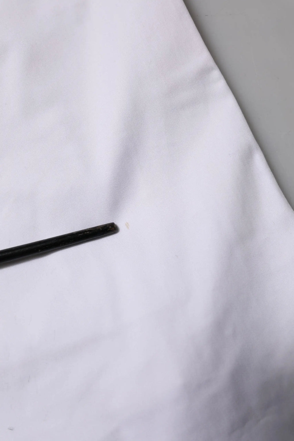 Stylo cylindrique noir posé sur un tissu blanc à côté d un short décontracté blanc en coton stretch dolce & gabbana