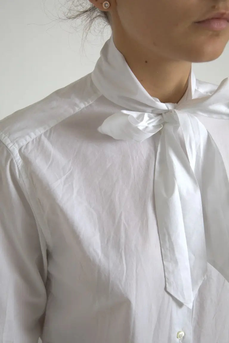 Blouse blanche dolce & gabbana en coton avec col ascot, manches longues et nœud délicat au col en tissu légèrement froissé