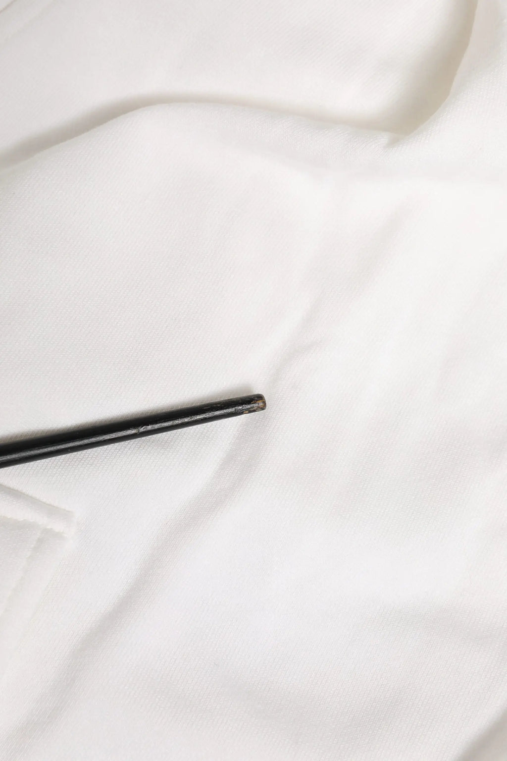 Un élégant chopstick noir mat posé sur un tissu blanc doux avec un short bermuda cargo en coton blanc dolce & gabbana