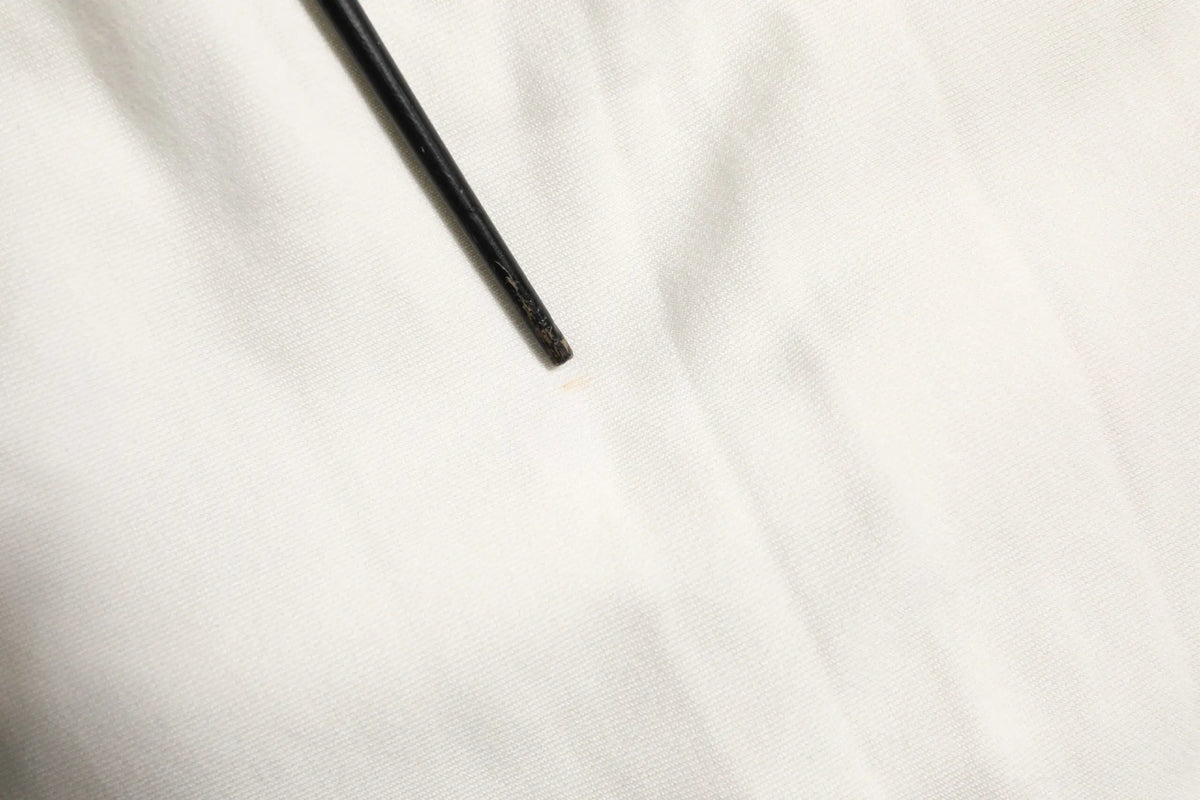 Objet cylindrique noir avec finition mate légèrement usée accompagné de bermuda cargo blanc en coton dolce & gabbana