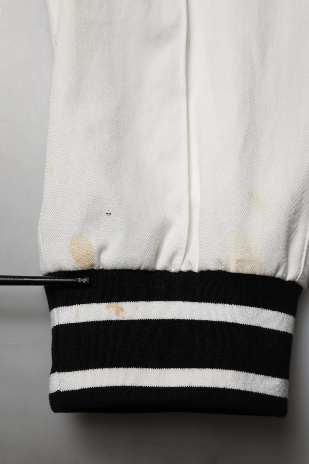Manche de veste varsity blanche dolce & gabbana avec bord rayé noir et blanc montrant des signes d’usure