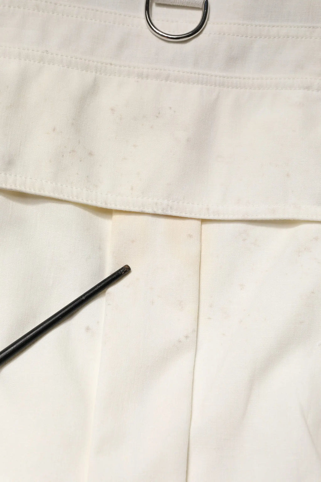 Pantalon en toile blanc dolce & gabbana avec anneau metal argenté à la taille et stylo noir posé dessus