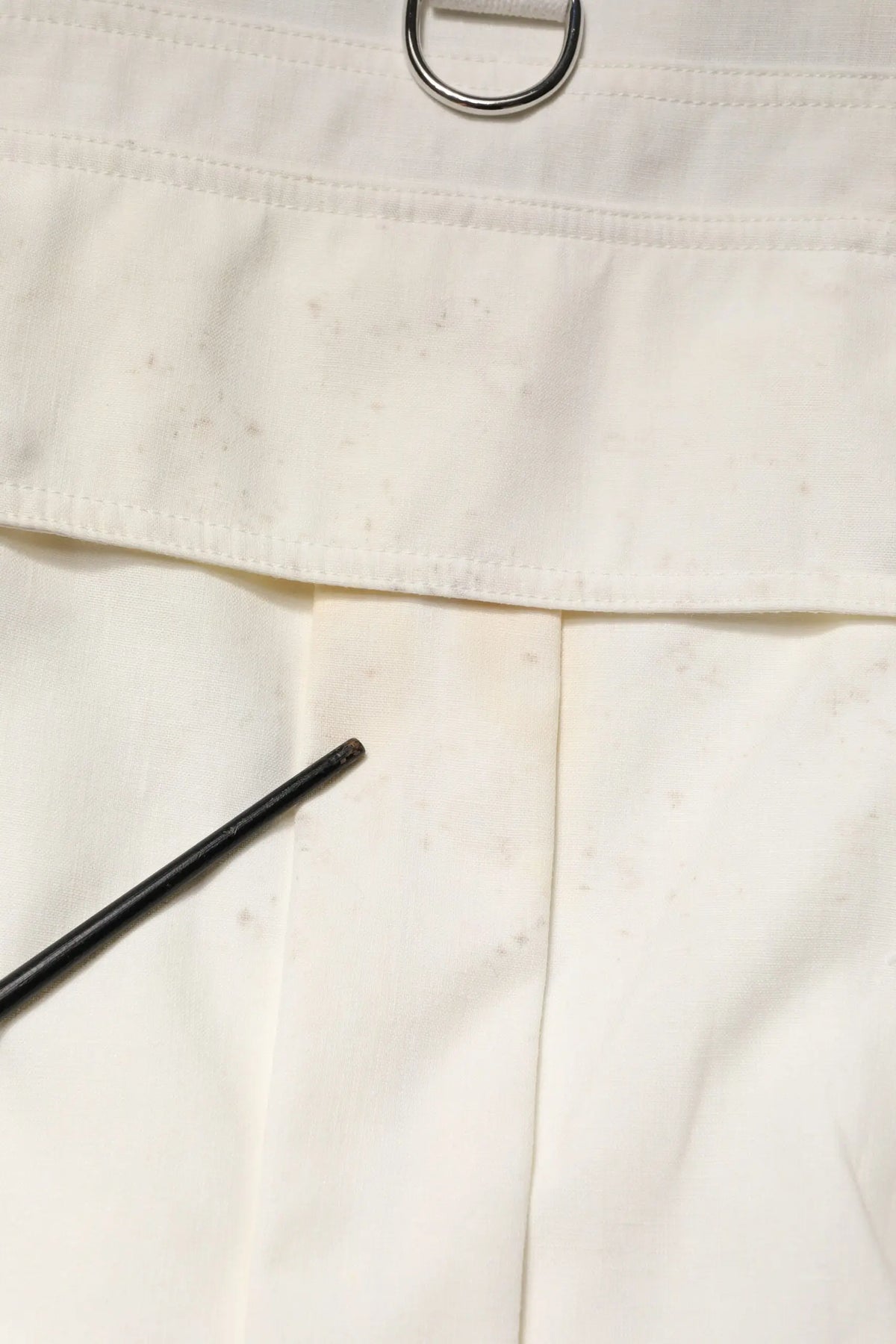 Pantalon en toile blanc dolce & gabbana avec anneau metal argenté à la taille et stylo noir posé dessus