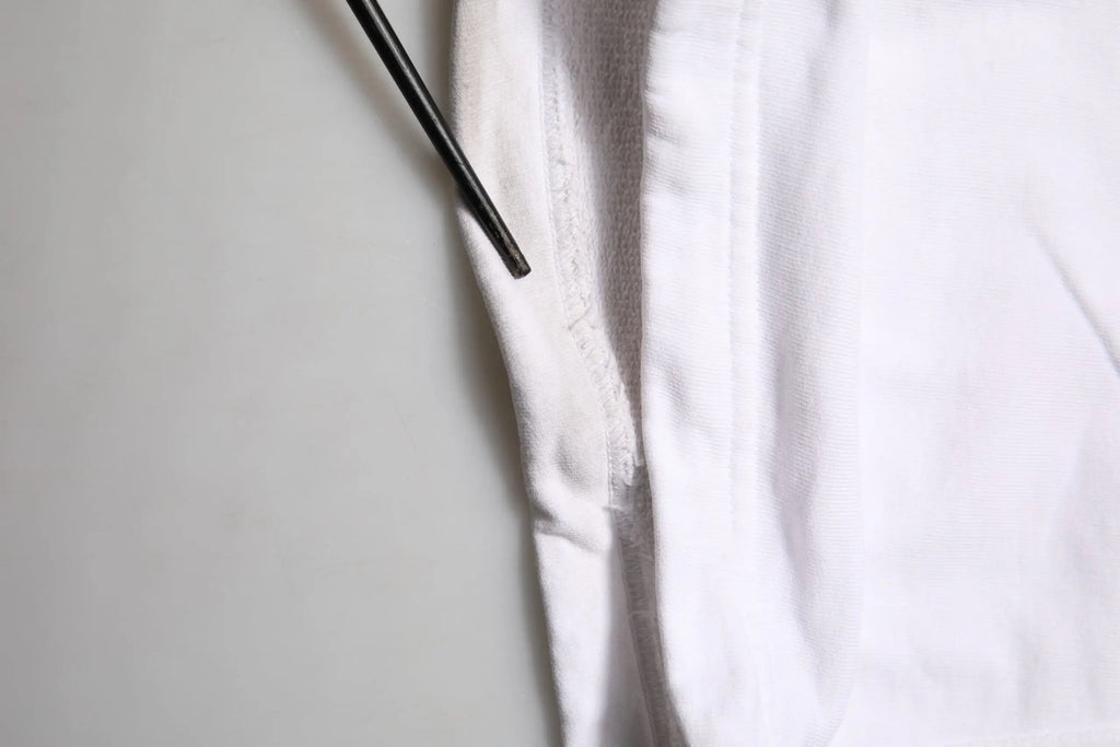 Un baguette noir élégant reposant sur le tissu blanc doux d un pantalon cargo en coton dolce gabbana avec patch logo