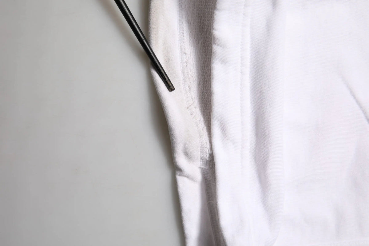 Un baguette noir élégant reposant sur le tissu blanc doux d un pantalon cargo en coton dolce gabbana avec patch logo