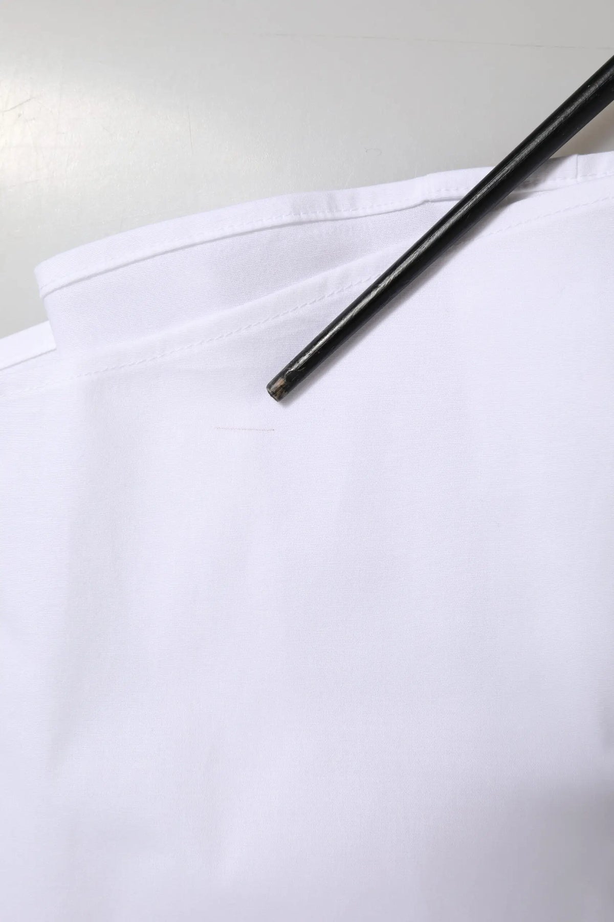 Un stylo noir élégant repose en diagonale sur le col blanc en coton de la chemise formelle dolce & gabbana