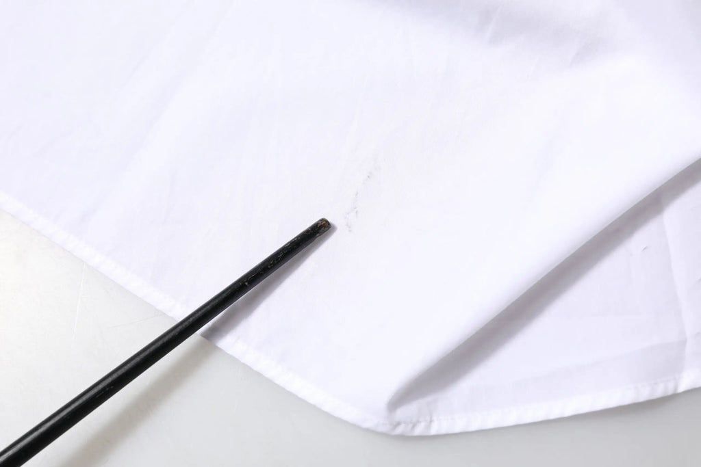 Bâtonnet noir posé sur un tissu blanc dune chemise à manches longues col en coton de dolce & gabbana