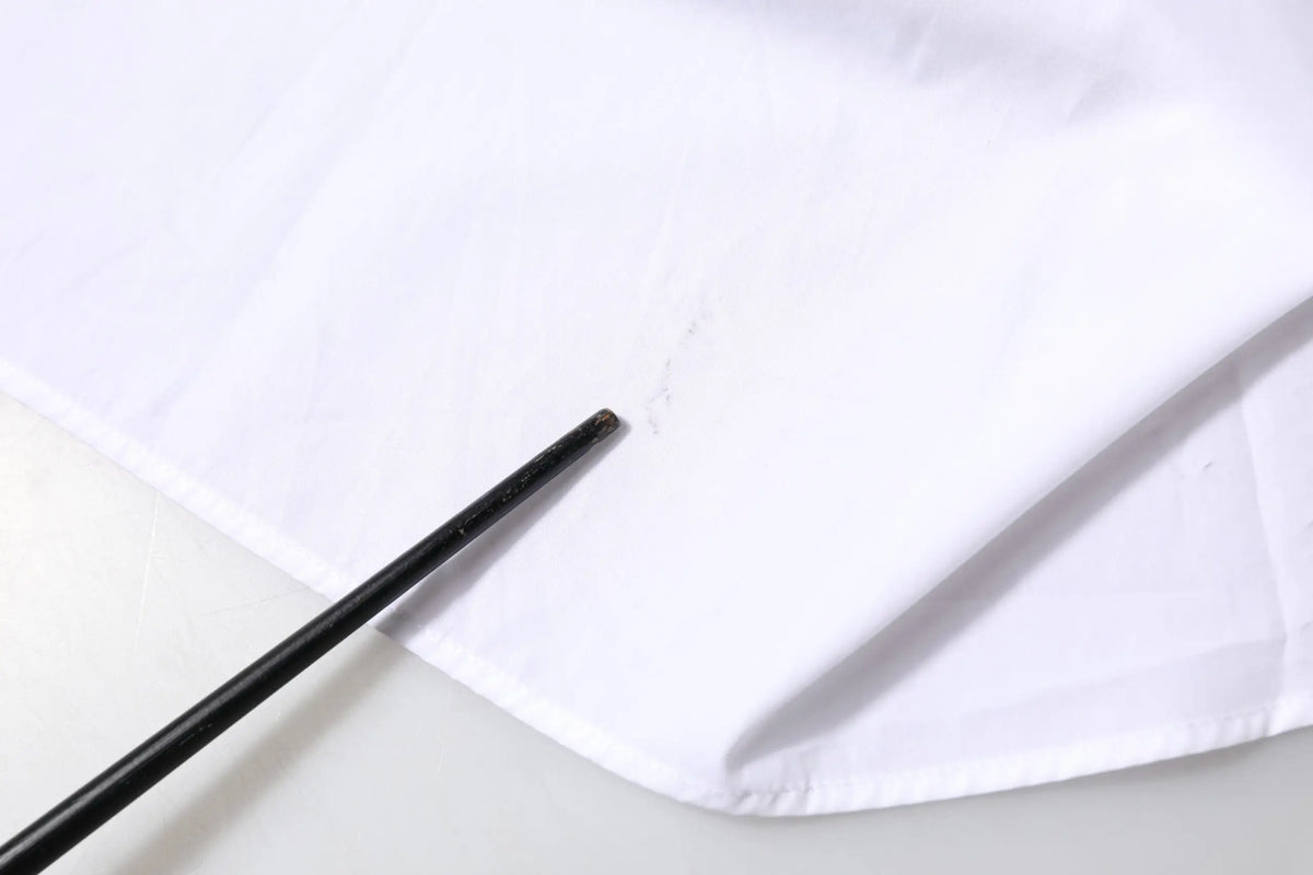 Bâtonnet noir posé sur un tissu blanc dune chemise à manches longues col en coton de dolce & gabbana