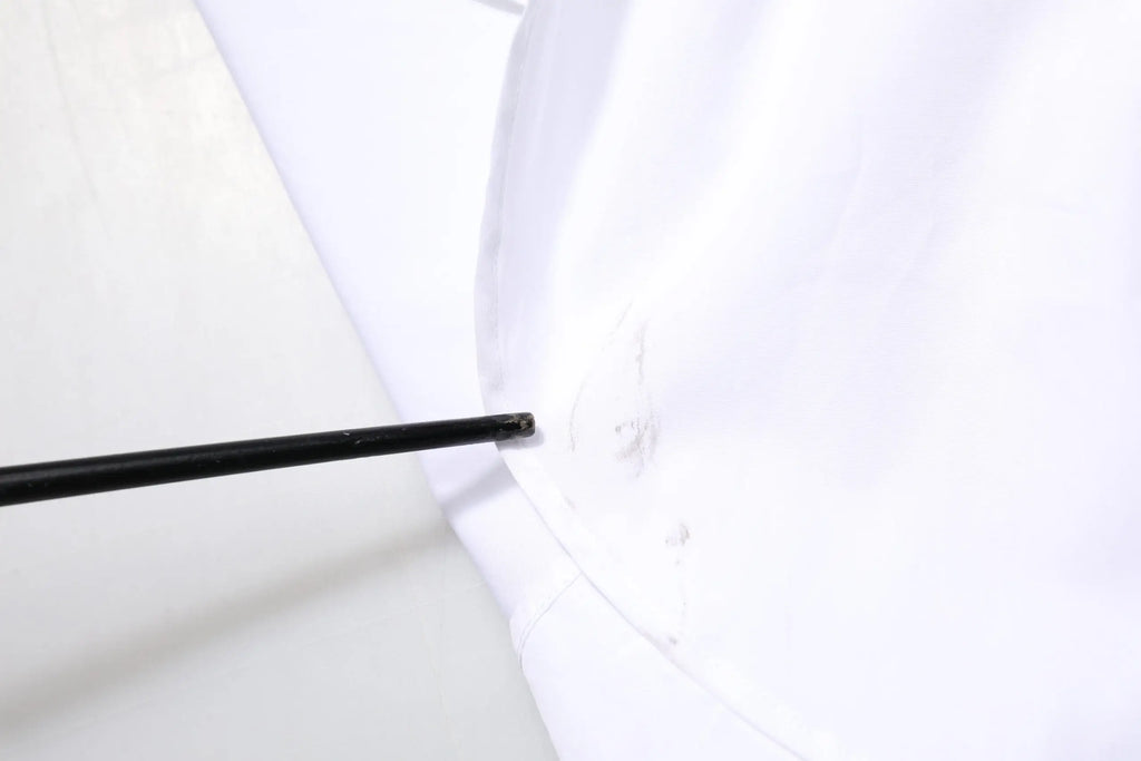 Outil noir inséré dans une couture de tissu blanc sur chemise blanche en coton à manches longues dolce & gabbana