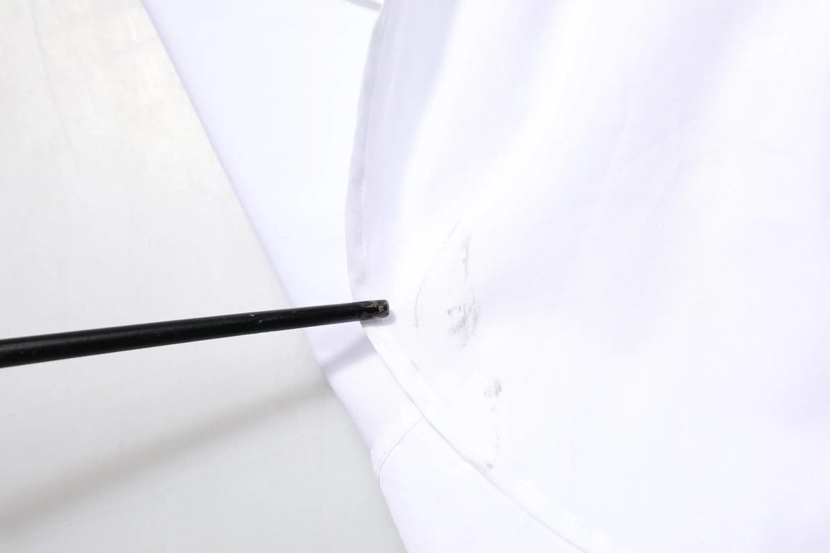 Outil noir inséré dans une couture de tissu blanc sur chemise blanche en coton à manches longues dolce & gabbana