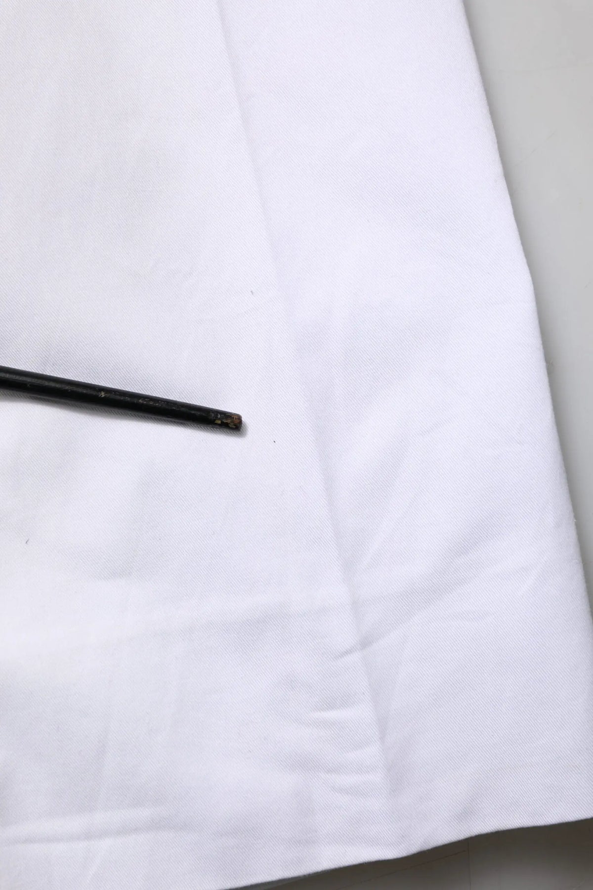 Bâtonnet noir posé sur tissu blanc avec pantalon slim formel blanc en coton dolce & gabbana