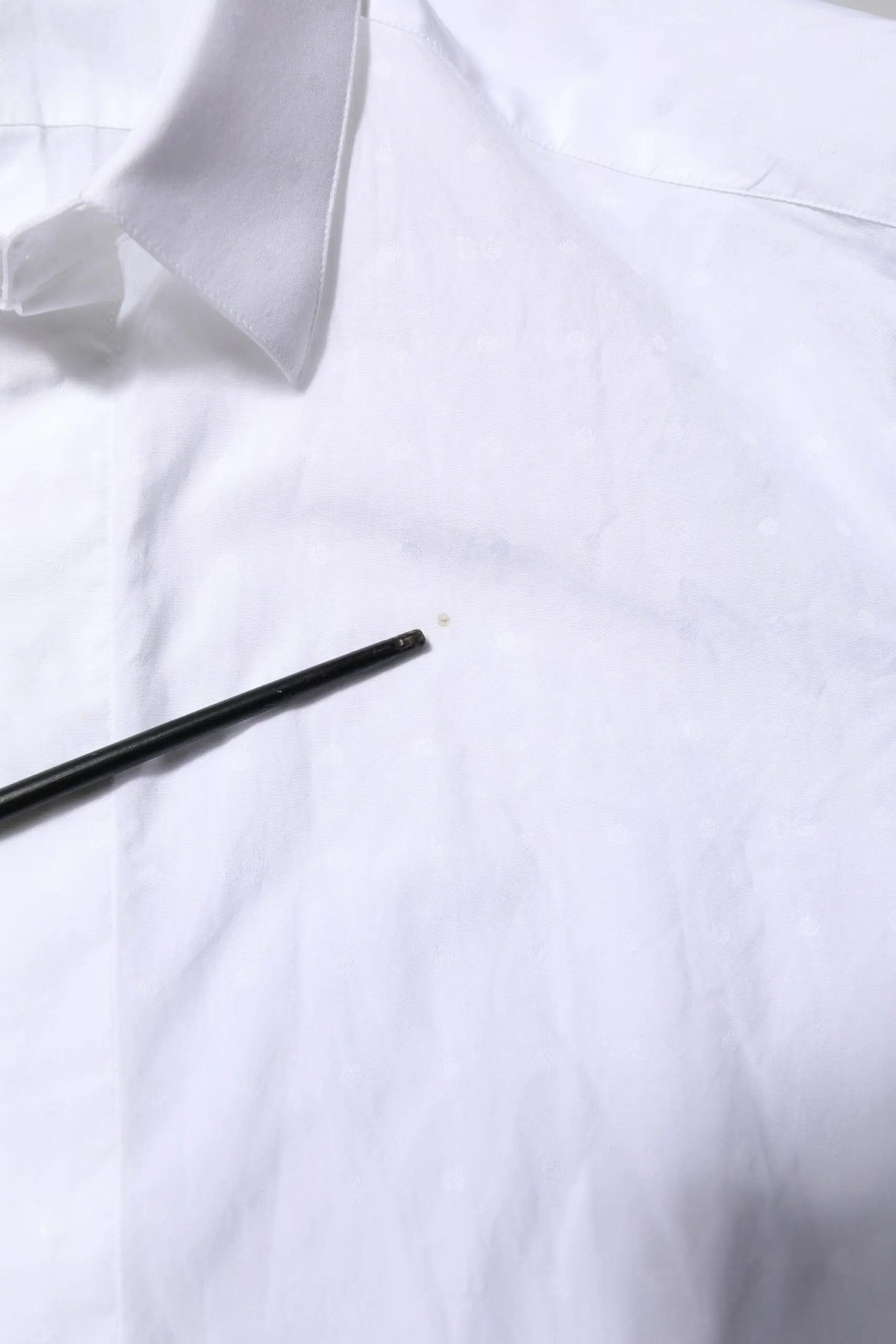 Un crayon noir repose en diagonale sur une chemise formelle blanche en coton dolce gabbana gold