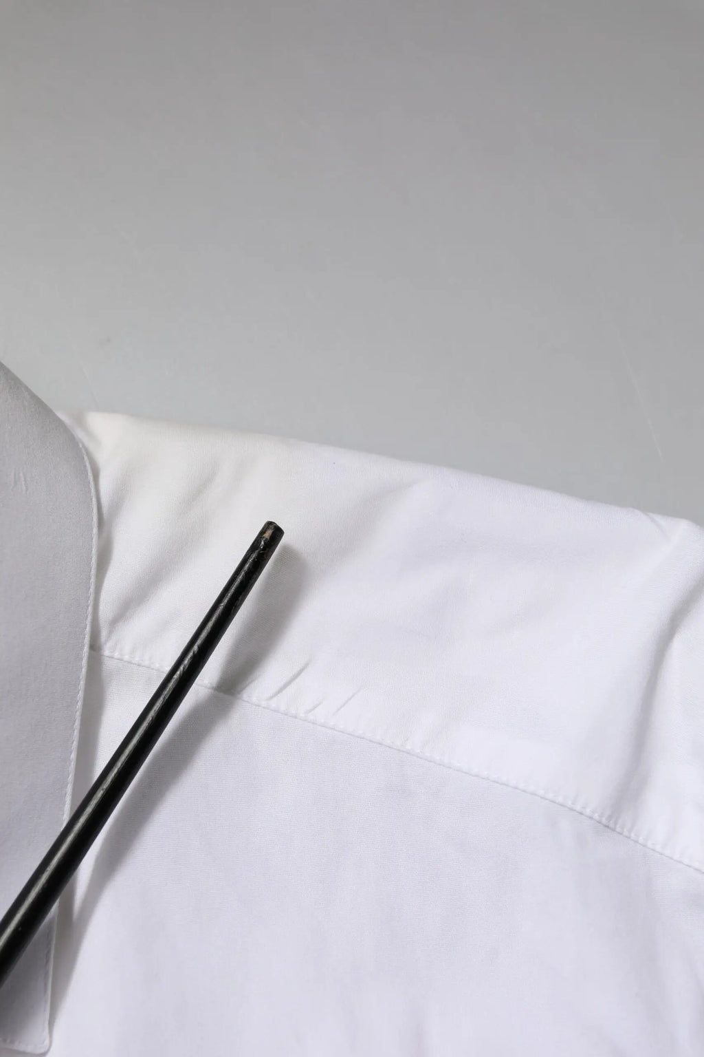 Stylo cylindrique noir posé sur tissu blanc avec chemise longue manche en coton blanc Dolce & Gabbana gold