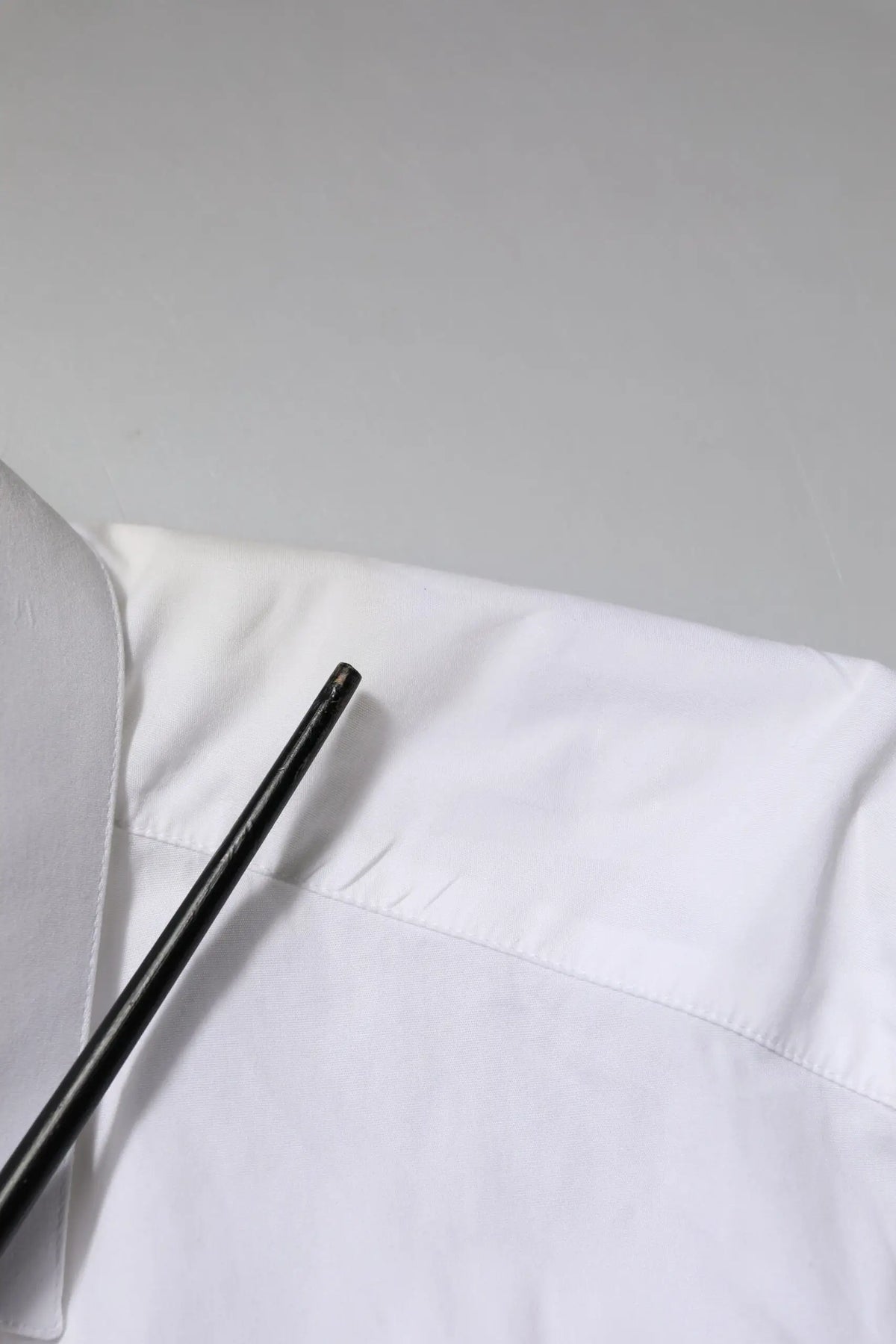 Stylo cylindrique noir posé sur tissu blanc avec chemise longue manche en coton blanc Dolce & Gabbana gold