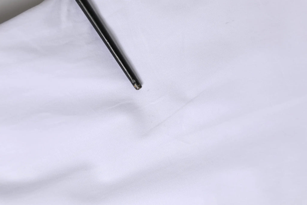 Stylo noir avec pointe métallique posé sur tissu blanc du chemise à manches longues Dolce & Gabbana coton blanc gold