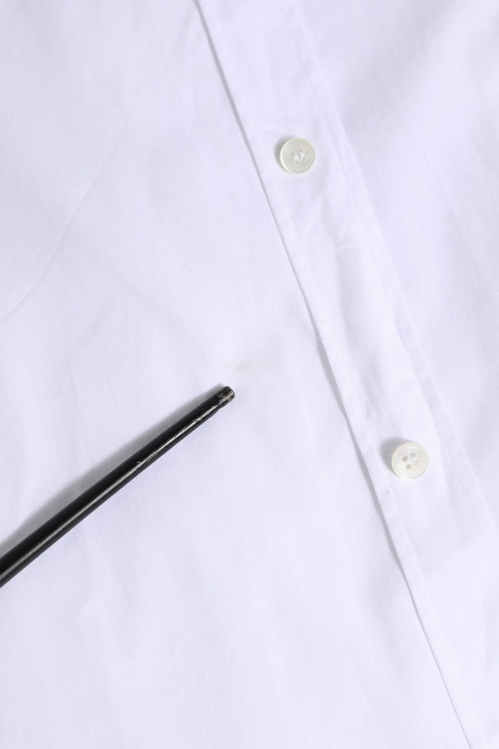 Un stylo noir élégant posé en diagonale sur une chemise blanche en coton à manches longues dolce gabbana gold