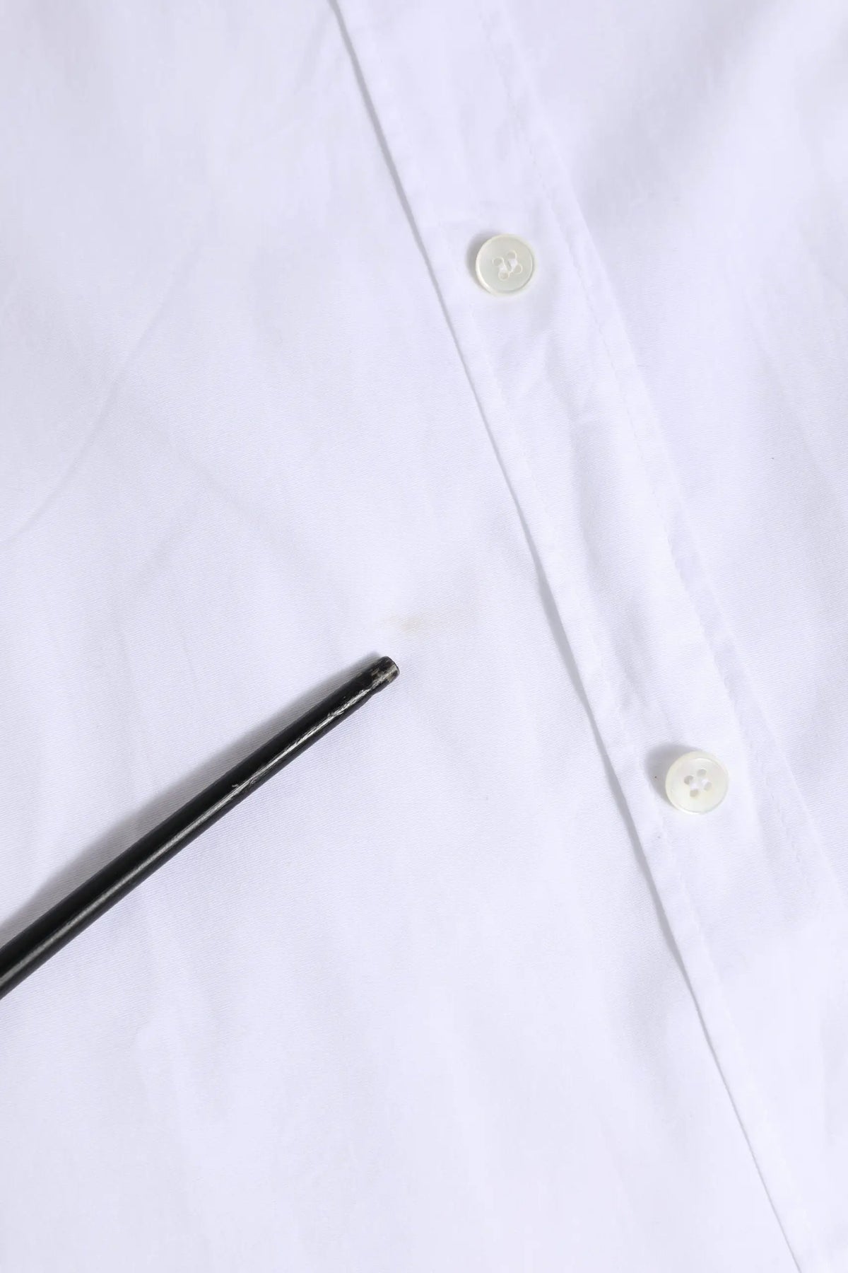 Un stylo noir élégant posé en diagonale sur une chemise blanche en coton à manches longues dolce gabbana gold