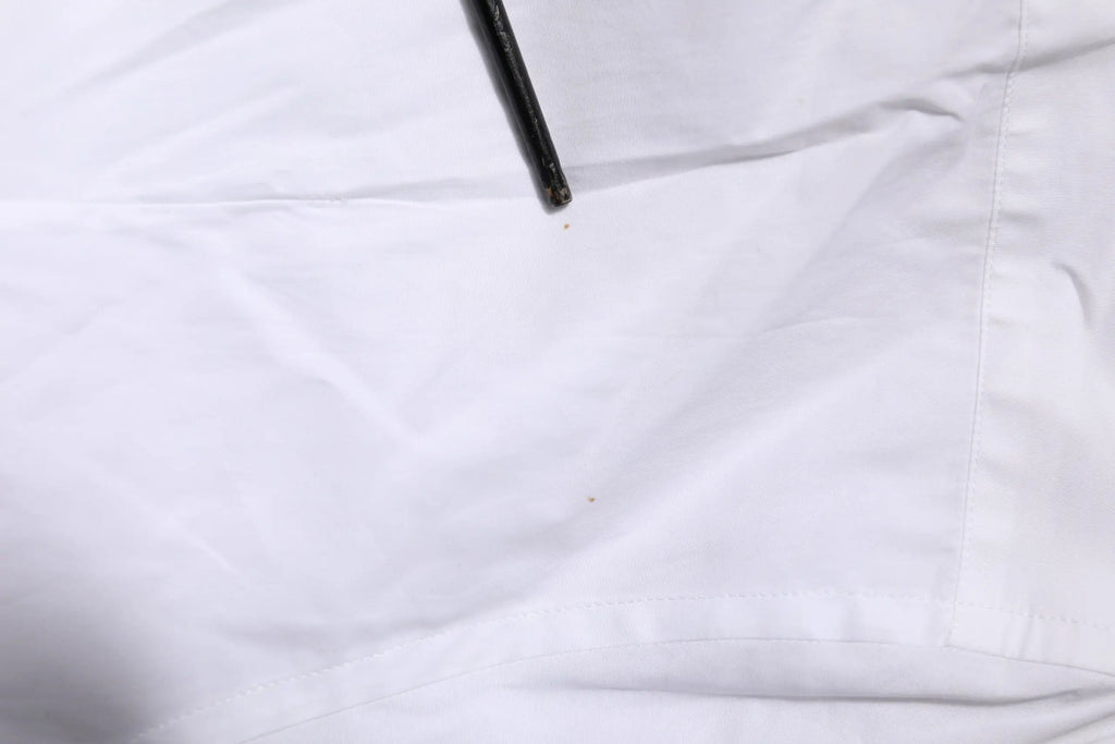 Détail de la pointe d’un stylo noir posé sur une chemise formelle blanche en coton à manches longues dolce & gabbana gold