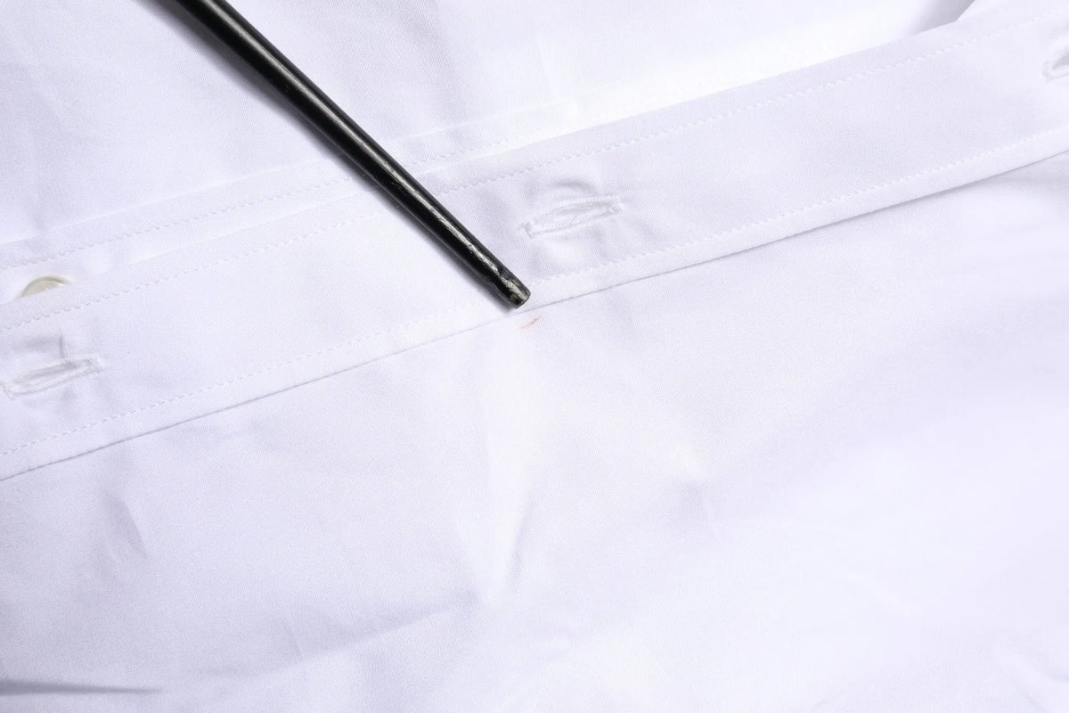 Un stylo noir élégant posé en diagonale sur le col d une chemise blanche en coton dolce & gabbana manches longues