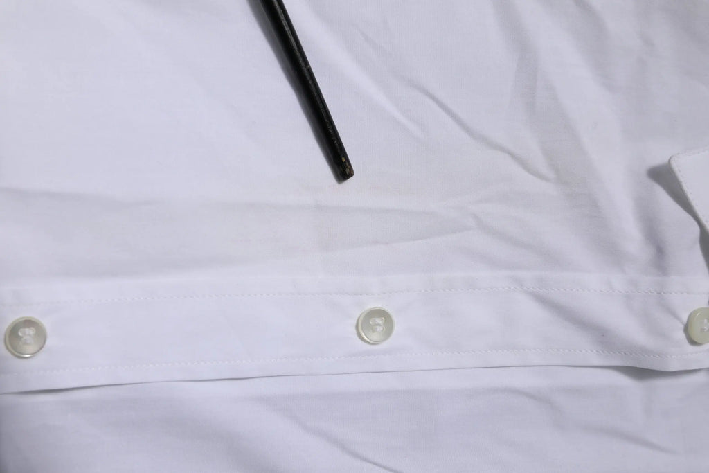Chemise blanche en coton dolce & gabbana à manches longues avec trois boutons assortis et stylo noir posé dessus