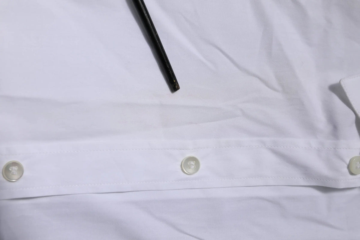 Chemise blanche en coton dolce & gabbana à manches longues avec trois boutons assortis et stylo noir posé dessus