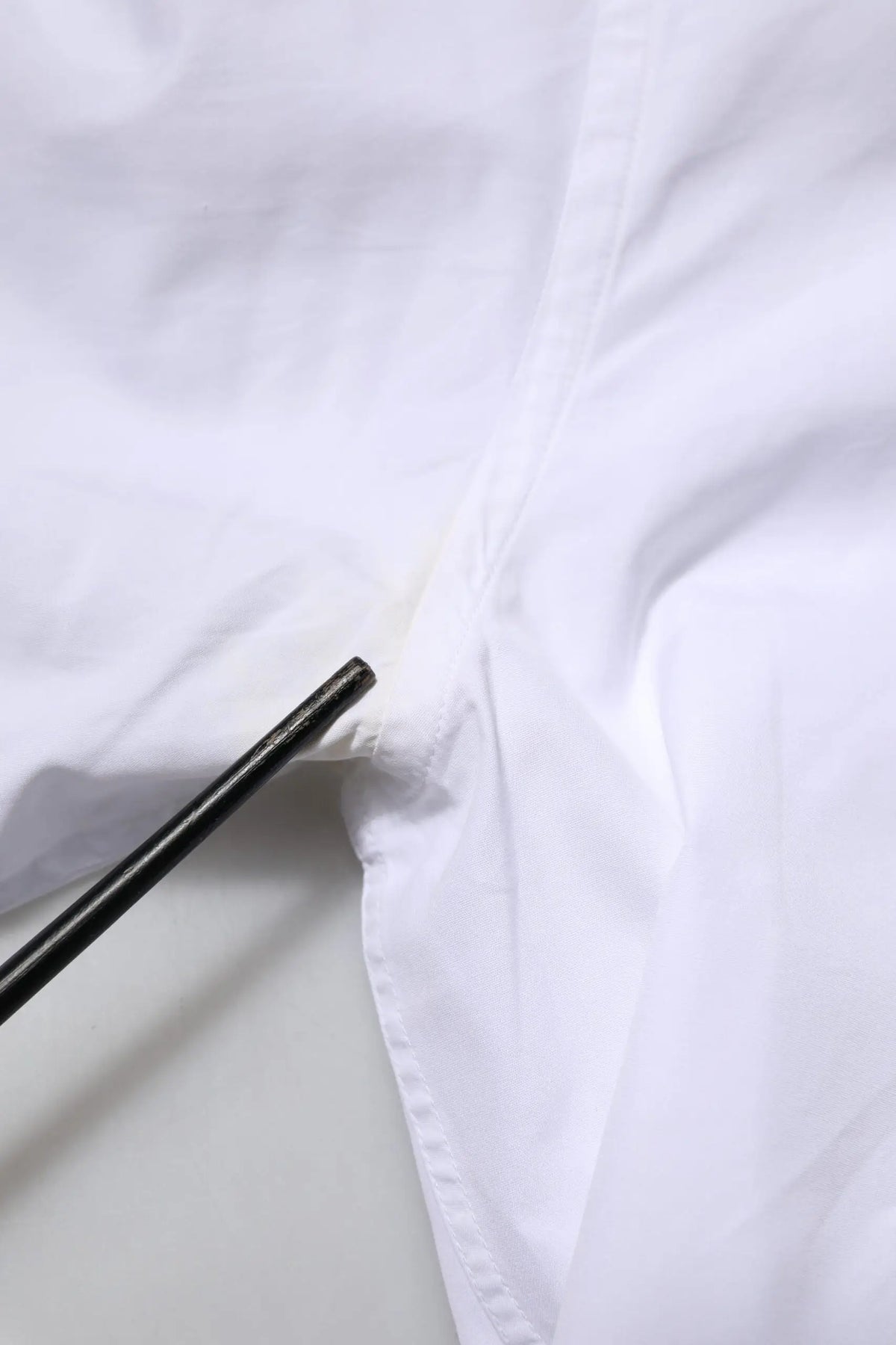 Chopsticks noirs posés sur un tissu blanc en coton froissé dolce & gabbana chemise homme manches longues or