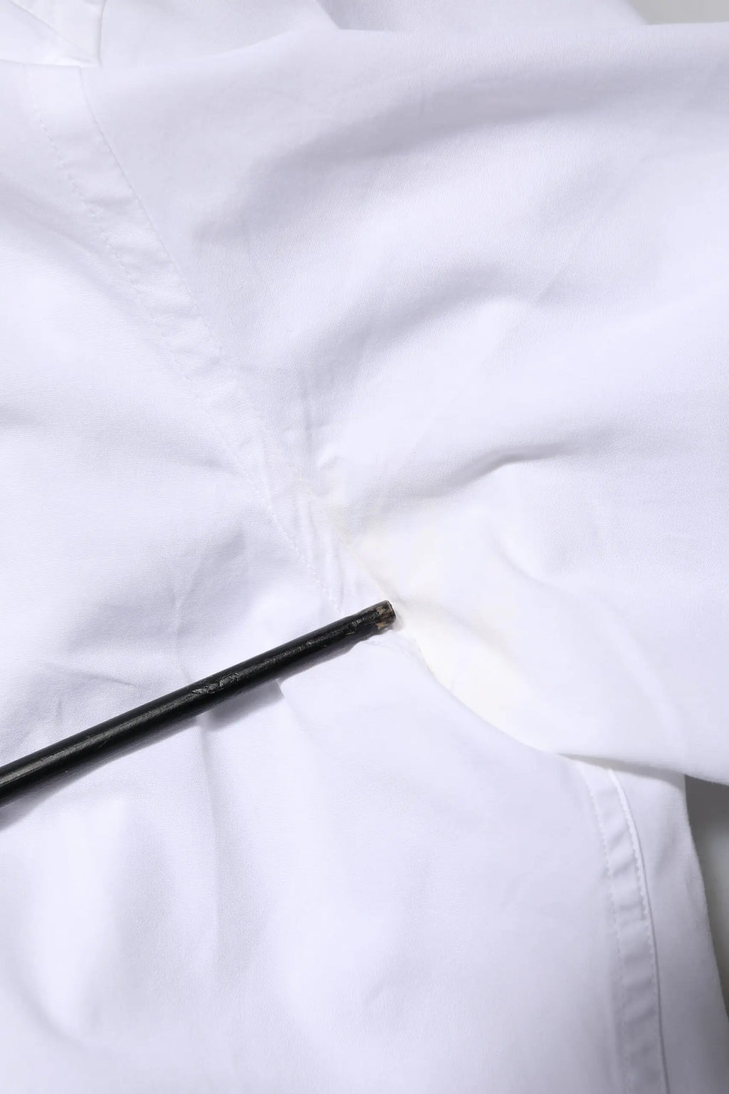 Un stylo noir élégant repose en diagonale sur une chemise dolce & gabbana blanche en coton à manches longues hommes