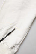 Un stylo noir mince repose en diagonale sur la manche en tissu blanc doux du sweat à capuche en coton dolce & gabbana