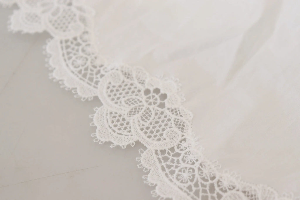 Dentelle blanche délicate en coton avec motifs floraux sur un haut col roulé dolce & gabbana