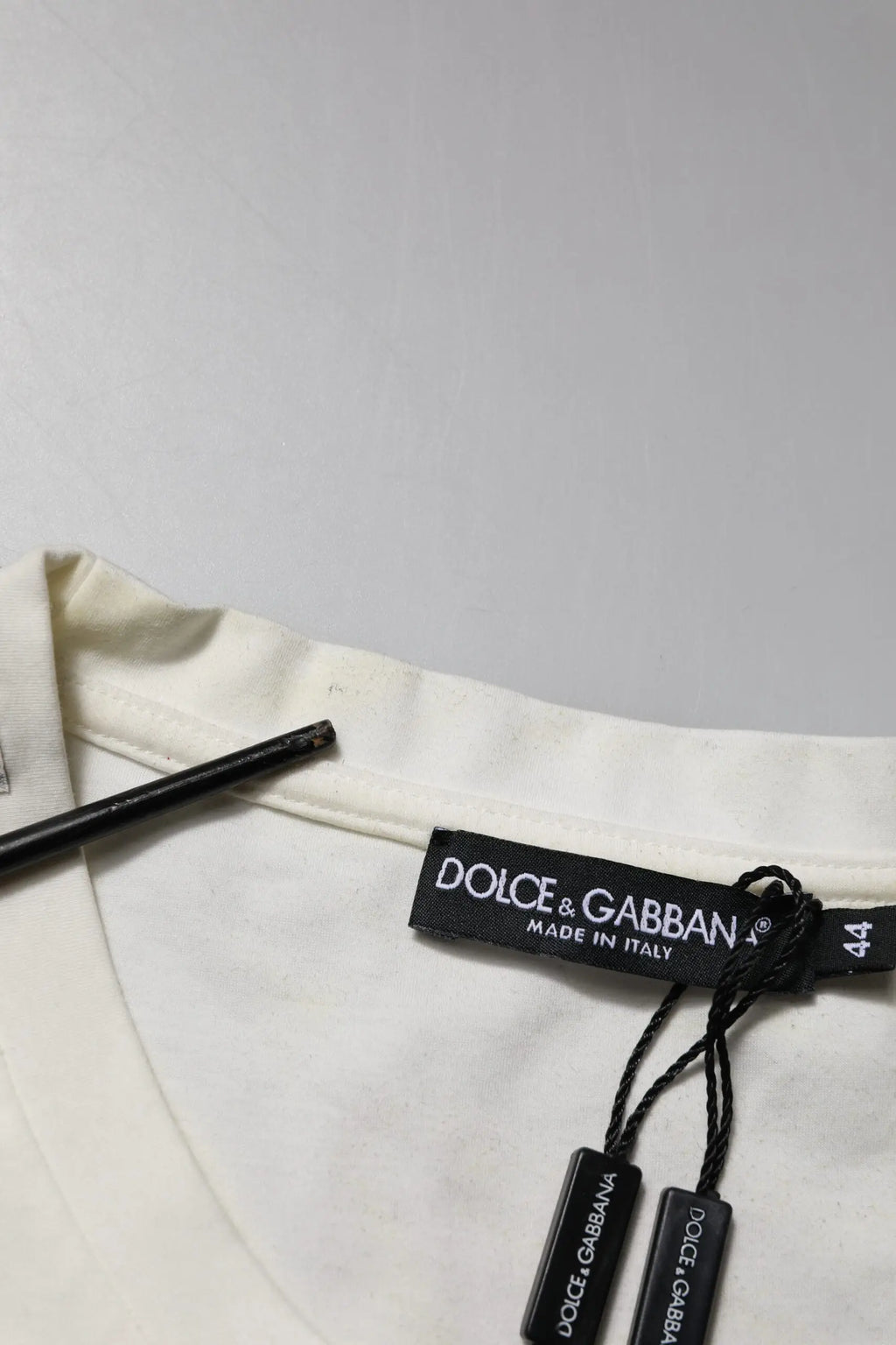 Étiquette noire dolce & gabbana avec lettrage blanc attachée à un t-shirt blanc en coton imprimé bandana
