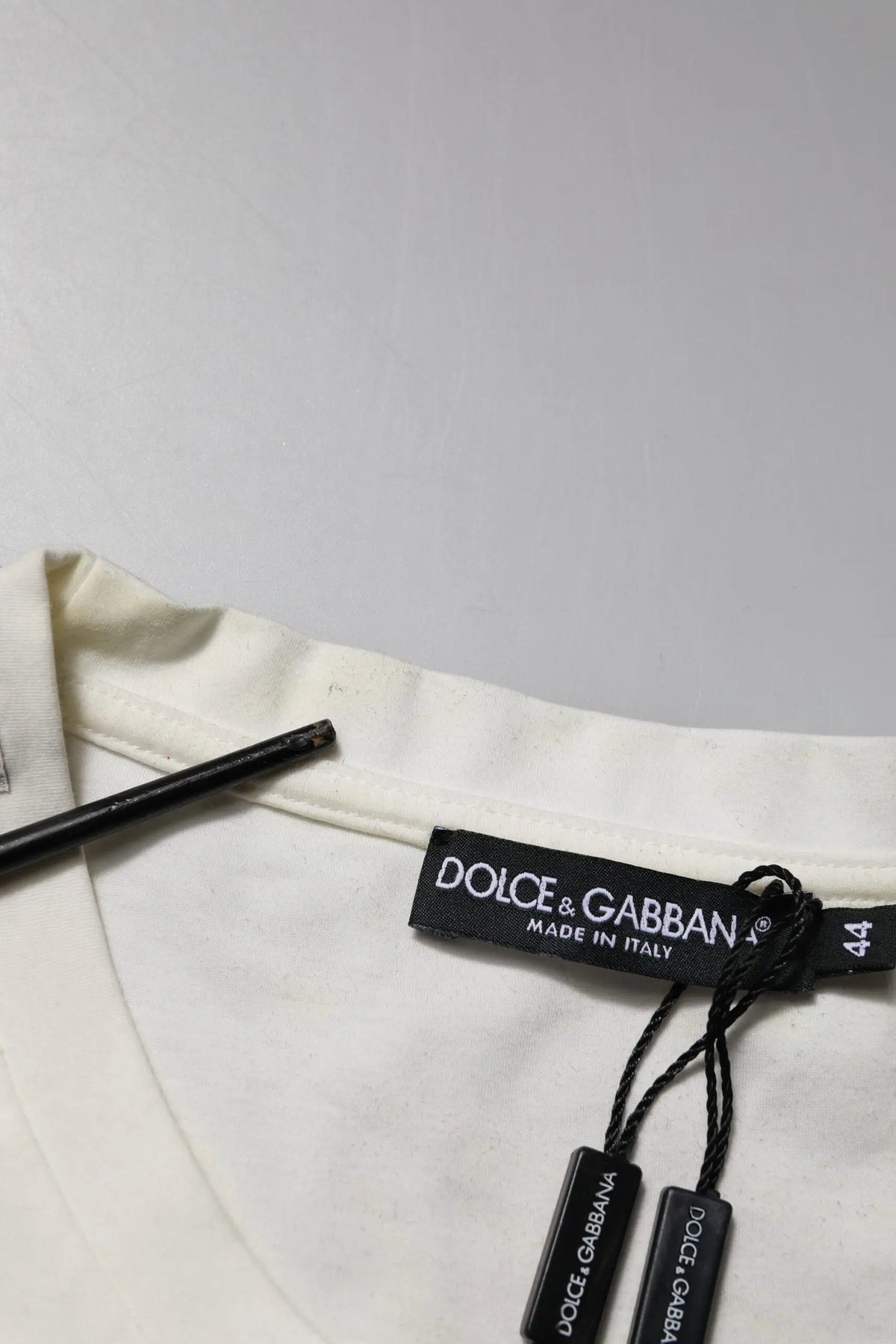 Étiquette noire dolce & gabbana avec lettrage blanc attachée à un t-shirt blanc en coton imprimé bandana