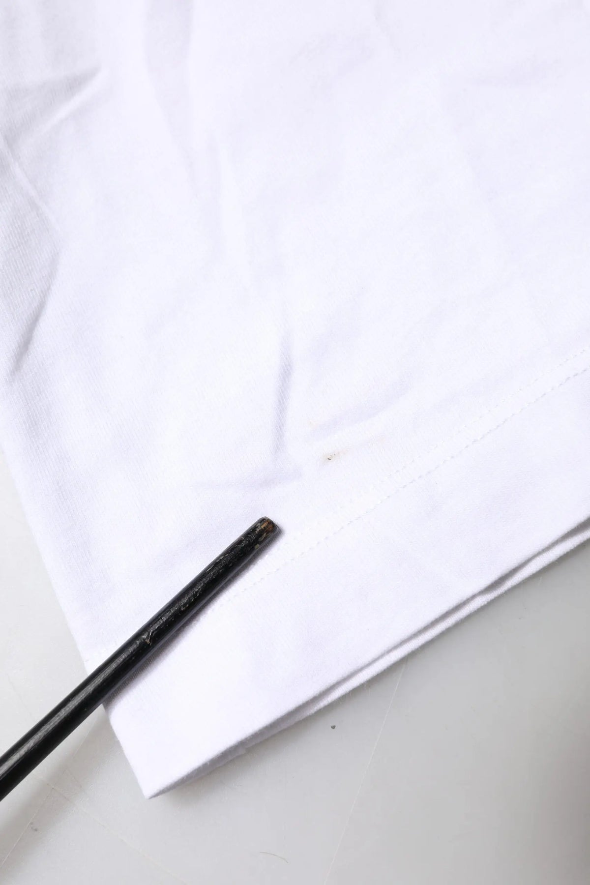 Chopsticks noirs en bois reposant sur un tissu blanc avec un t-shirt dolce & gabbana en coton blanc à logo brodé