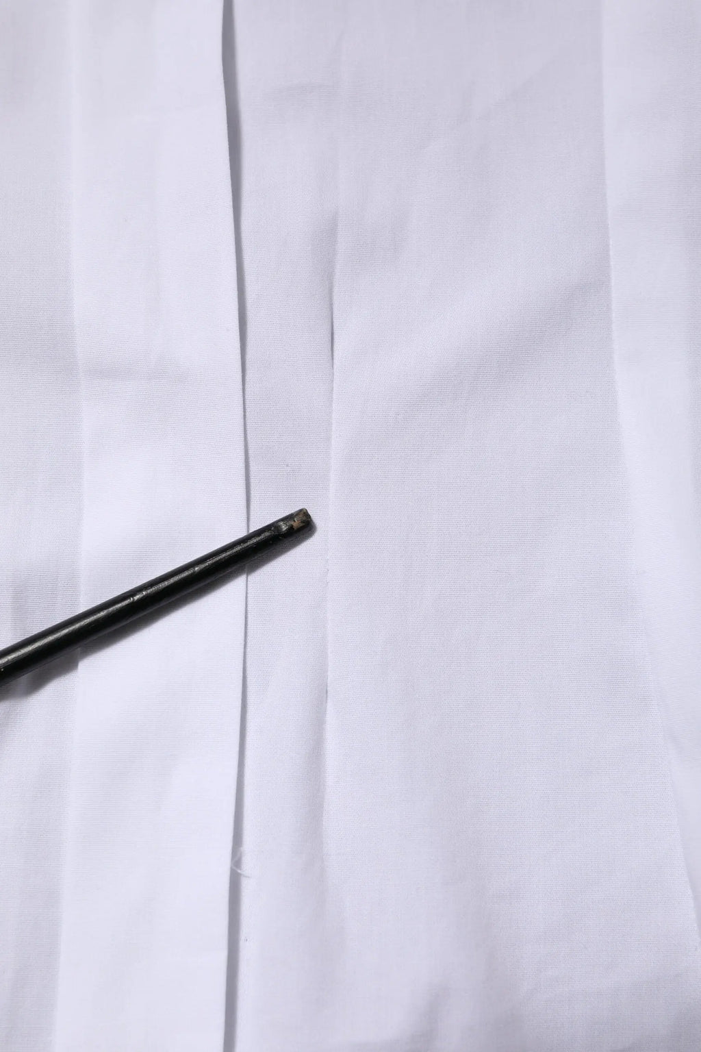 Un crayon noir mince posé en diagonale sur une chemise blanche en coton à manches longues avec col de dolce & gabbana