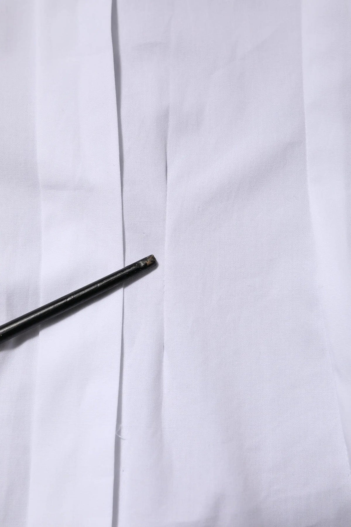 Un crayon noir mince posé en diagonale sur une chemise blanche en coton à manches longues avec col de dolce & gabbana
