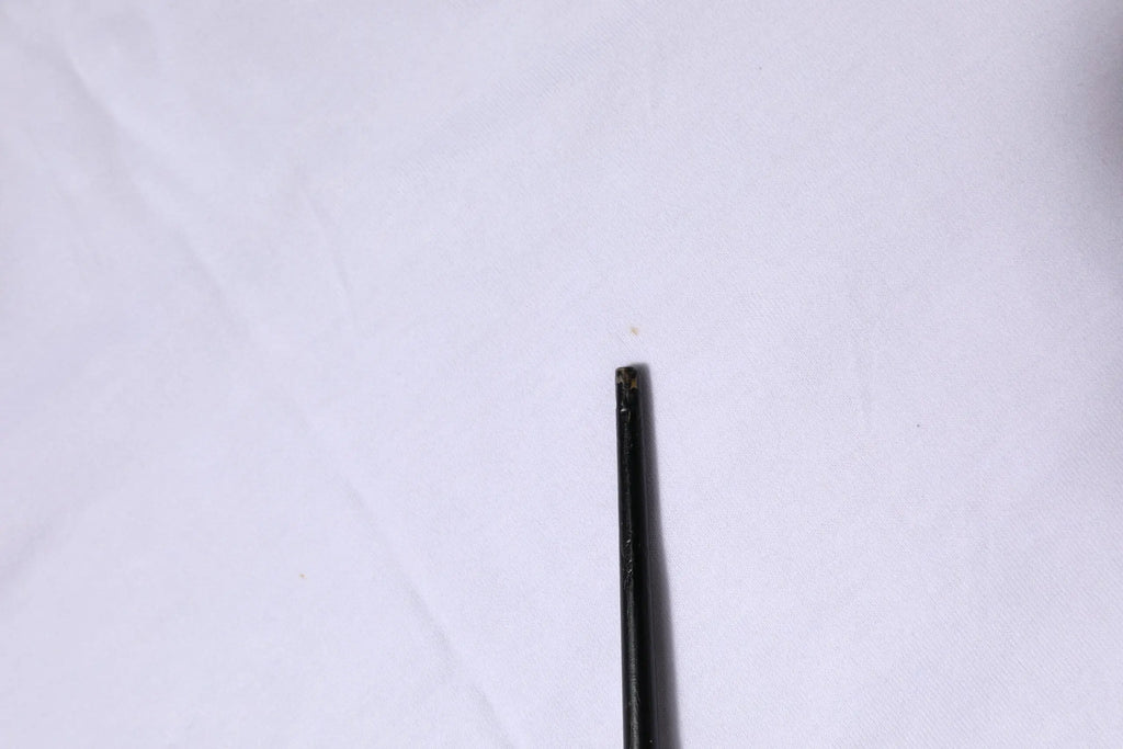 Objet cylindrique noir avec surface légèrement texturée et petites imperfections sur tshirt dolce & gabbana coton blanc manches courtes col rond