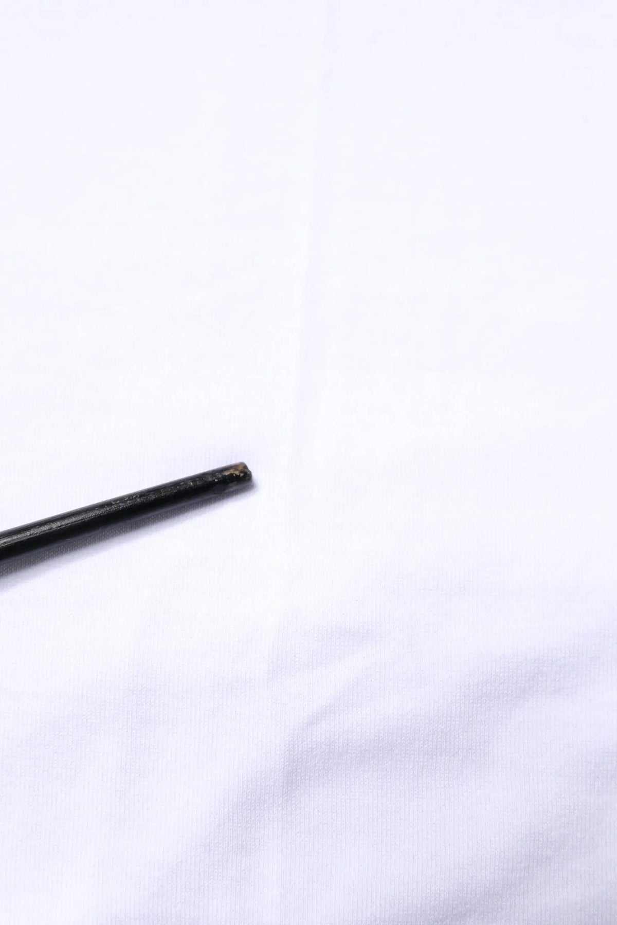 Objet cylindrique noir avec surface légèrement usée et texturée associé au débardeur blanc en coton sans manches dolce gabbana