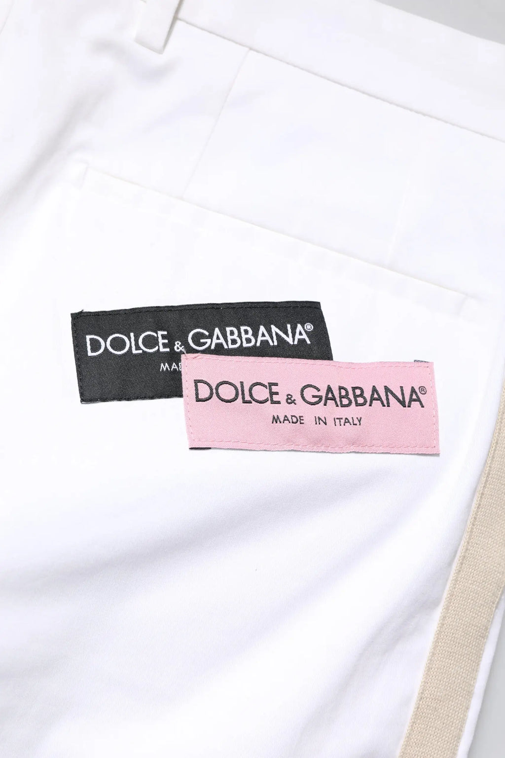 Étiquette blanche dolce & gabbana sur pantalon homme blanc en coton avec étiquettes noires et roses made in italy