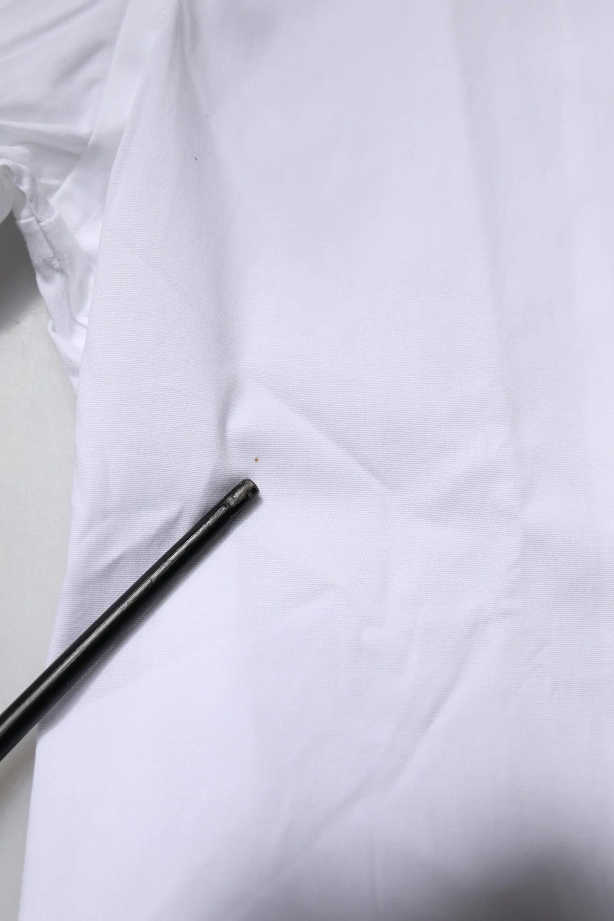 Crayon noir posé sur tissu blanc près d’une chemise formelle dolce & gabbana en coton stretch blanc gold