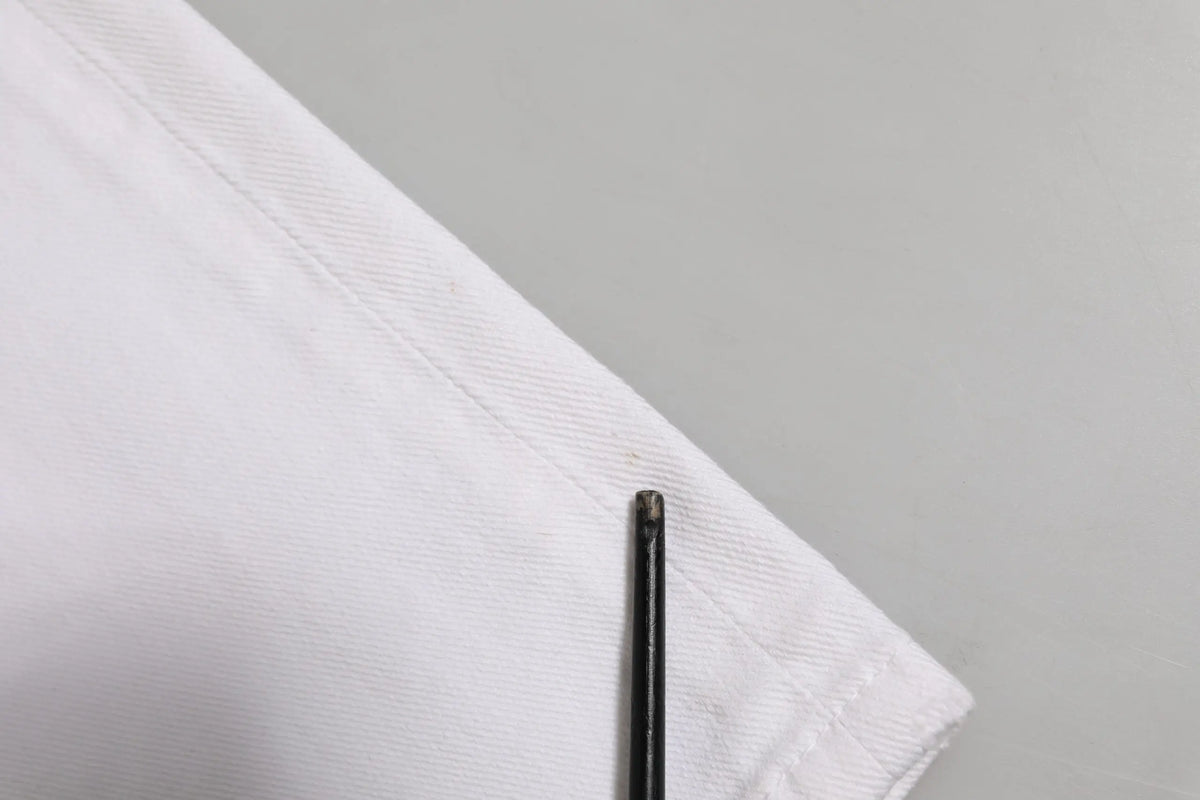 Une aiguille à coudre noire repose sur le tissu blanc net d un jean boyfriend délavé en coton blanc dolce gabbana
