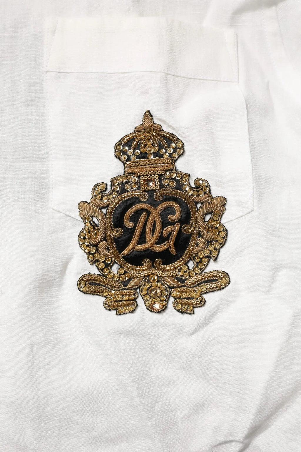 Patch logo dolce gabbana brodée or avec perles et motif couronne sur tissu noir pour chemise formelle blanche dg crown
