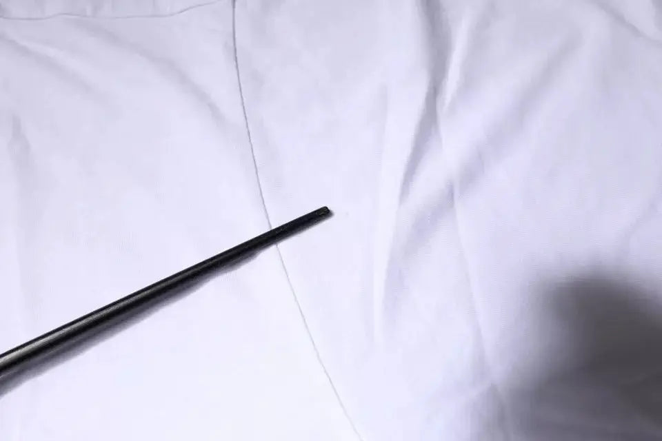 Stylo cylindrique noir posé sur tissu blanc à côté d’un t-shirt dolce & gabbana blanc en coton avec logo dg col rond