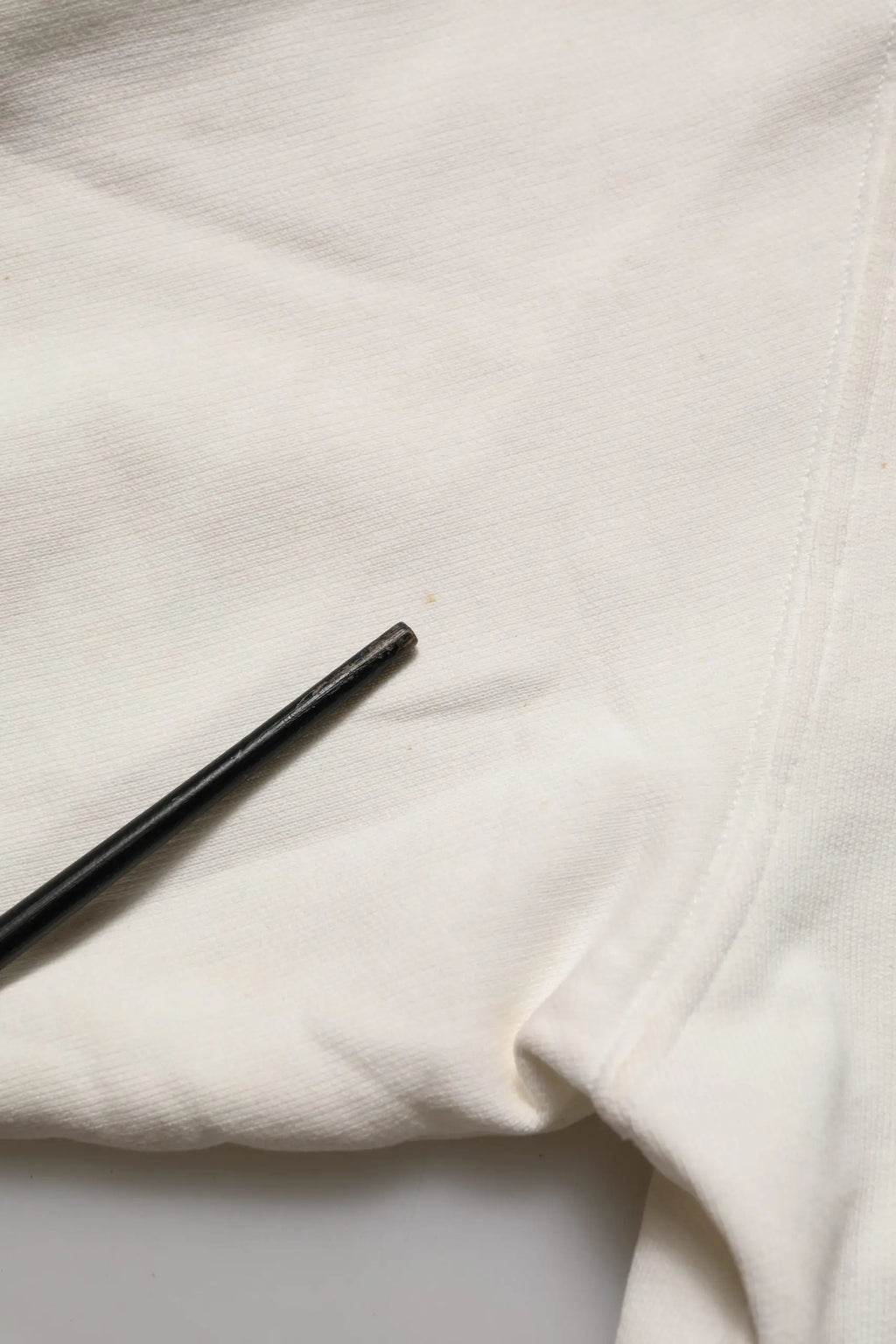 Chopsticks noirs reposant sur un tissu blanc dans un sweat blanc dolce & gabbana dg logo col rond en coton