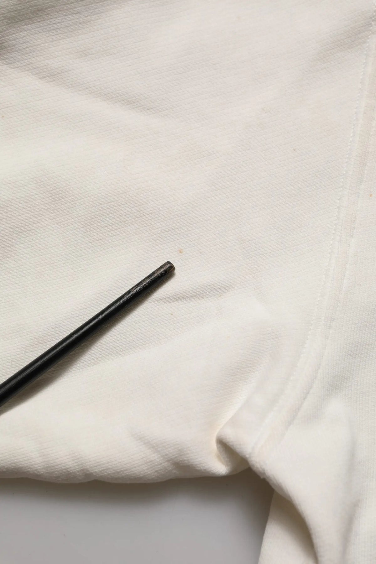 Chopsticks noirs reposant sur un tissu blanc dans un sweat blanc dolce & gabbana dg logo col rond en coton