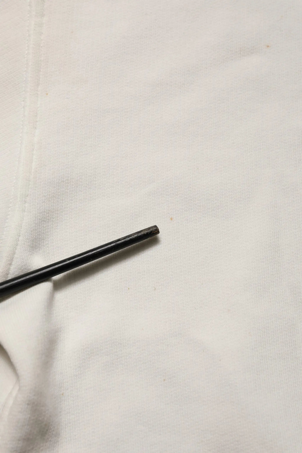 Chopstick cylindrique noir reposant sur un tissu blanc avec un sweat-shirt dolce & gabbana blanc logo dg col rond