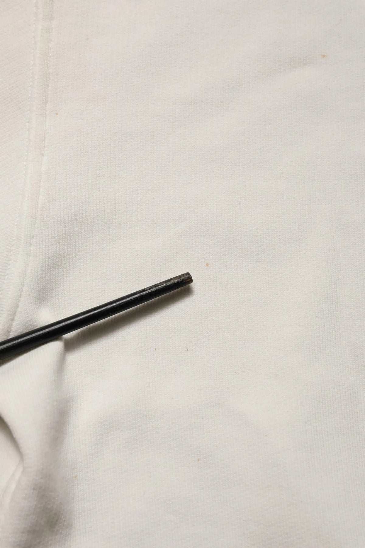 Chopstick cylindrique noir reposant sur un tissu blanc avec un sweat-shirt dolce & gabbana blanc logo dg col rond