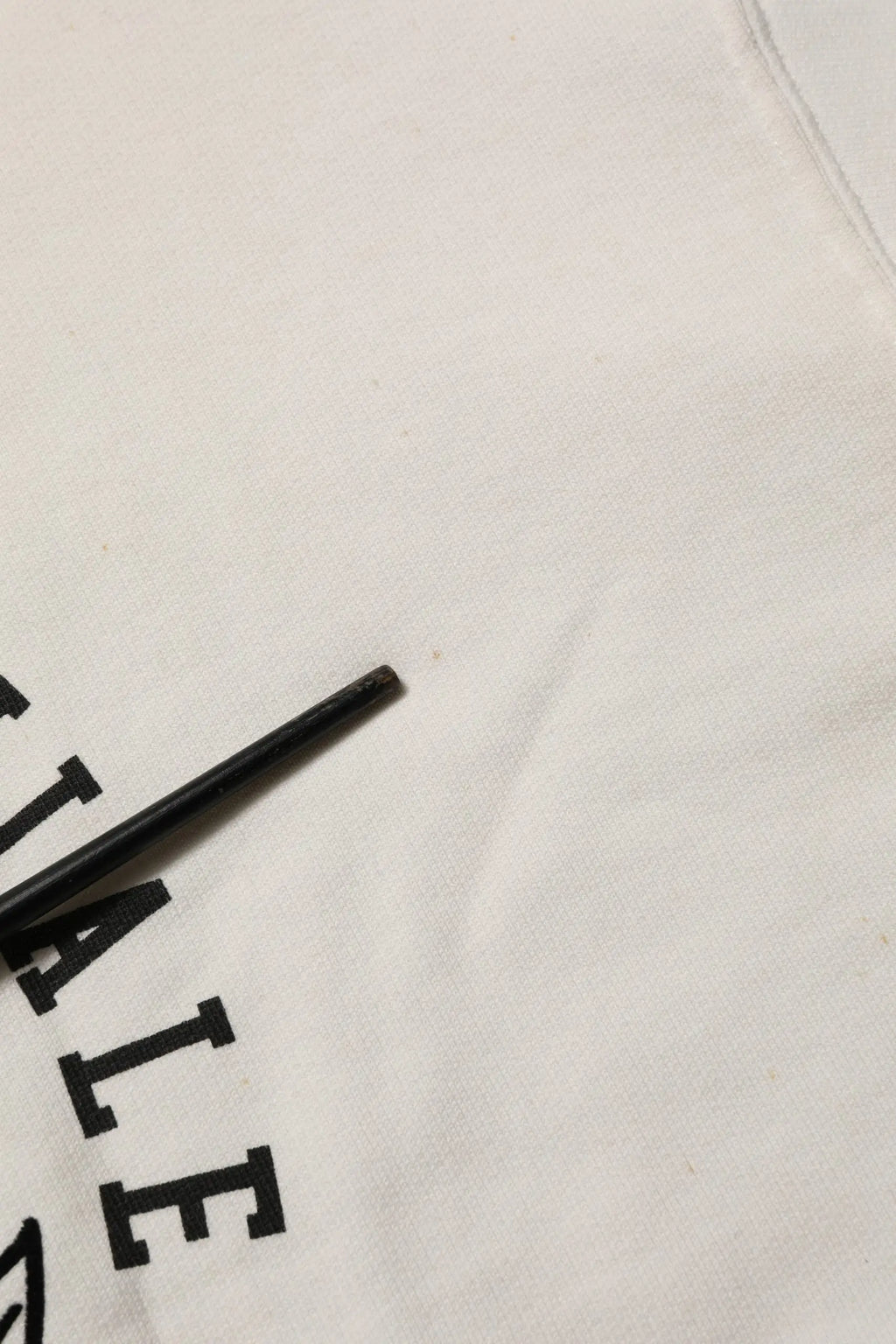 Chopstick noir reposant sur un tissu blanc avec logo dg noir sur sweat shirt dolce & gabbana col rond blanc