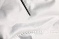 Un objet cylindrique noir élégant posé sur un tissu blanc doux en polyester dans la veste bomber dolce & gabbana blanche dg logo